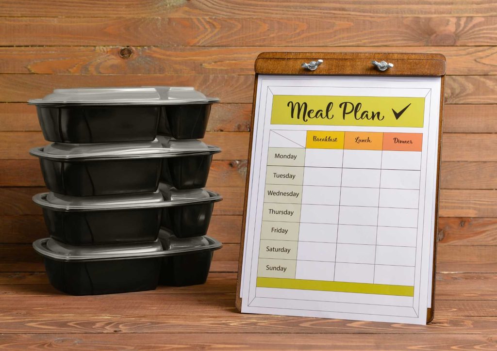 Healthy Meal Plans for Weight Loss: How to Build One That Lasts 21 A neatly arranged meal plan printable on a rustic wooden table, outlining meals for the week with designated sections.