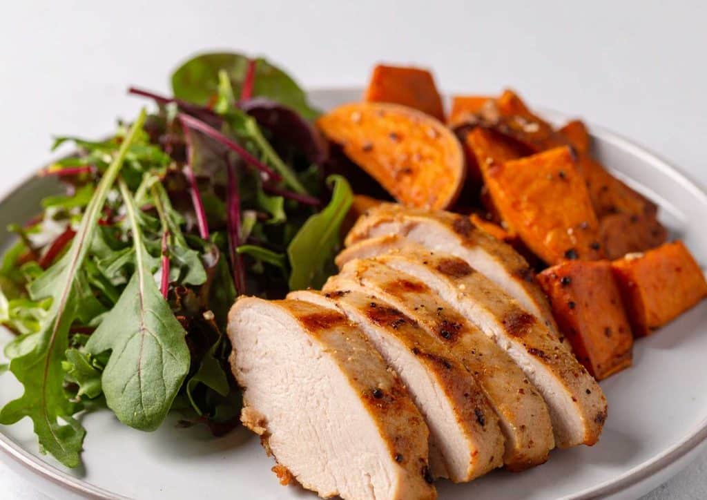 Healthy Dinners for Weight Loss: Easy Weeknight Ideas 35 Grilled chicken breast served with sweet potato and a fresh garden salad on a white plate.