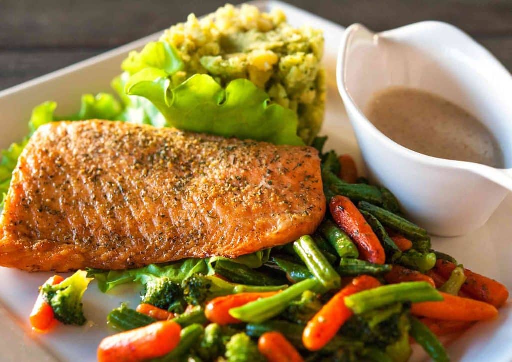 Easy Meals for Weight Loss When You're Short on Time 39 A plate featuring grilled salmon, colorful vegetables, and a side dish, arranged appetizingly.