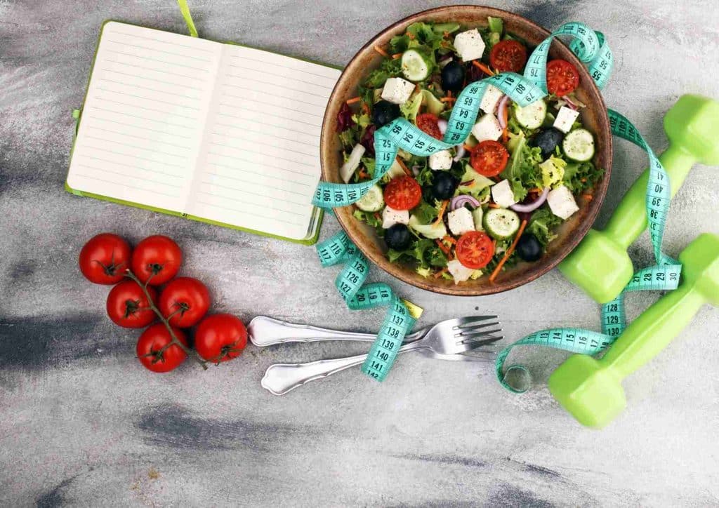 Easy Meals for Weight Loss When You're Short on Time 42 A bowl of salad accompanied by a measuring tape, symbolising health and portion control.
