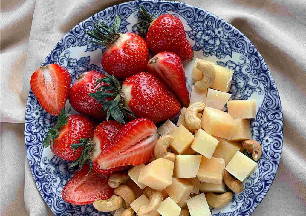 Healthy Snacks for Weight Loss That Actually Keep You Full 7 A plate featuring an assortment of fresh fruits and various cheeses arranged artfully.
