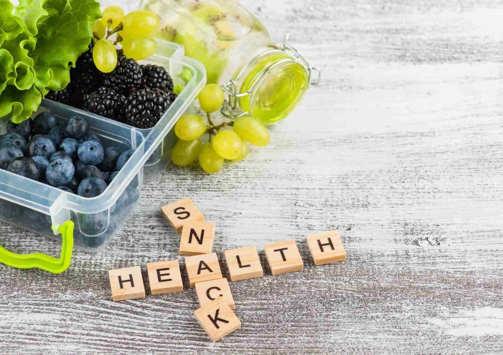 Healthy Snacks for Weight Loss That Actually Keep You Full 9 Fresh fruits and healthy snacks artfully presented on a wooden table, highlighting a commitment to nutritious choices.