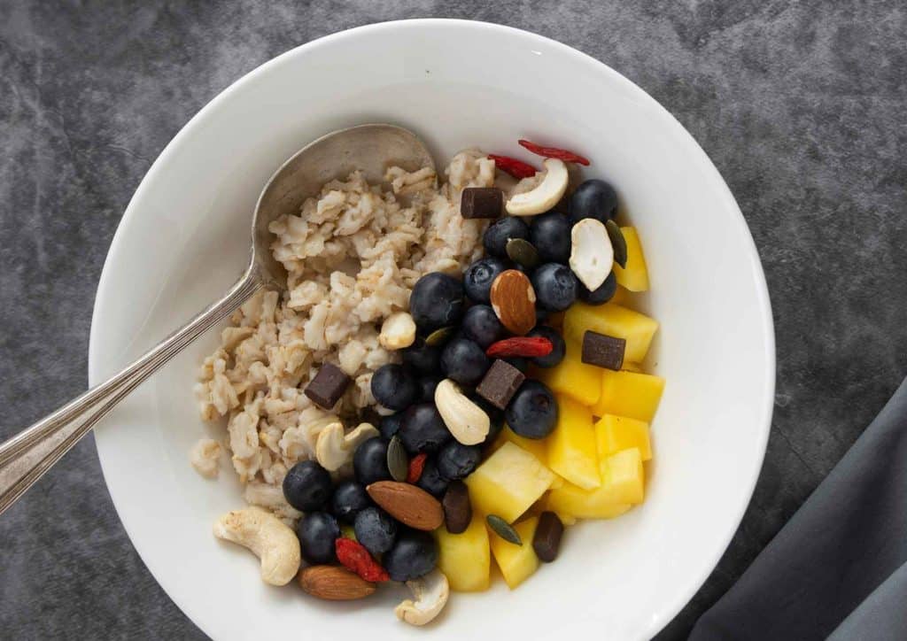 Healthy Snacks for Weight Loss That Actually Keep You Full 14 A bowl of oatmeal topped with fresh blueberries, mango slices, and a sprinkle of nuts for added texture.