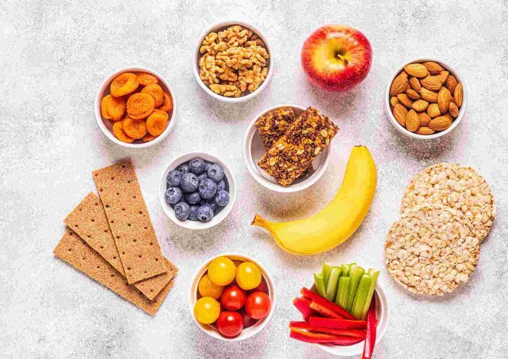Healthy Snacks for Weight Loss That Actually Keep You Full 18 Various healthy snacks, such as sliced fruits, nuts, and seeds, neatly arranged in bowls on a table.