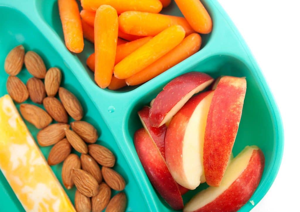 Healthy Snacks for Weight Loss That Actually Keep You Full 25 A plate featuring sliced carrots, scattered almonds, and cubes of cheese arranged artfully.