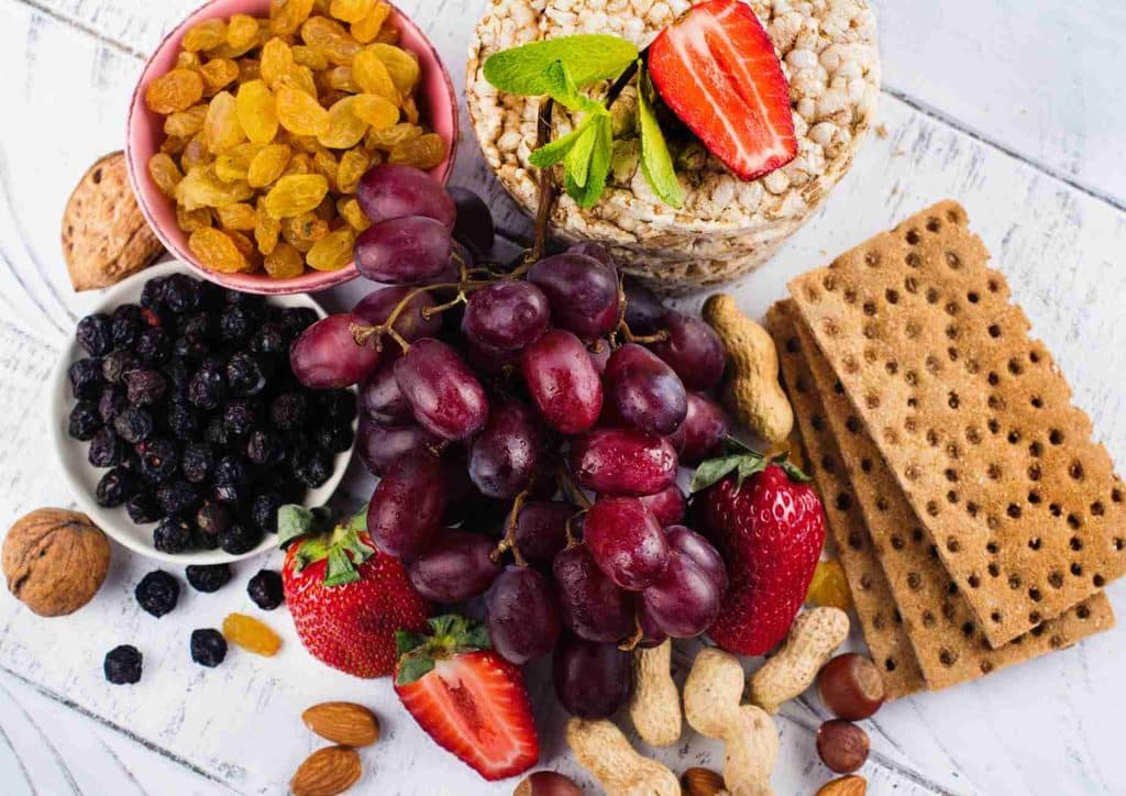 Healthy Snacks for Weight Loss That Actually Keep You Full 24 A white table featuring a diverse selection of fruits and nuts, highlighting their natural colours and shapes.