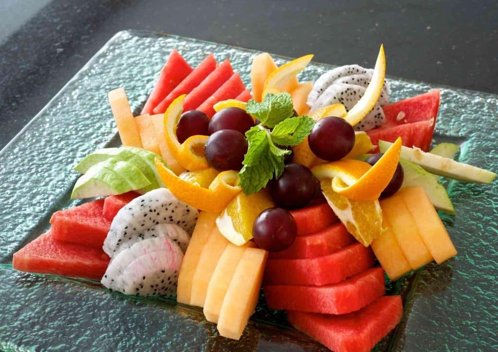 High Fibre Diet for Weight Loss: Why Fibre Keeps You Full 39 A clear glass plate displaying a vibrant arrangement of sliced fruits, featuring apples, bananas, and grapes.
