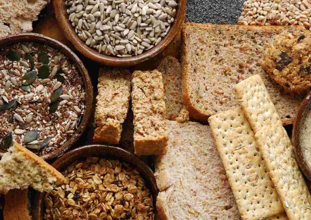 High Fibre Diet for Weight Loss: Why Fibre Keeps You Full 42 An assortment of breads, cereals, and various food items displayed on a wooden table.