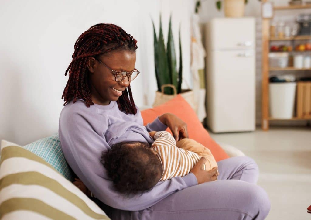 Losing Weight While Breastfeeding: What's Safe and Realistic 73 A woman sits on a couch, breastfeeding her baby, creating a nurturing and intimate atmosphere.