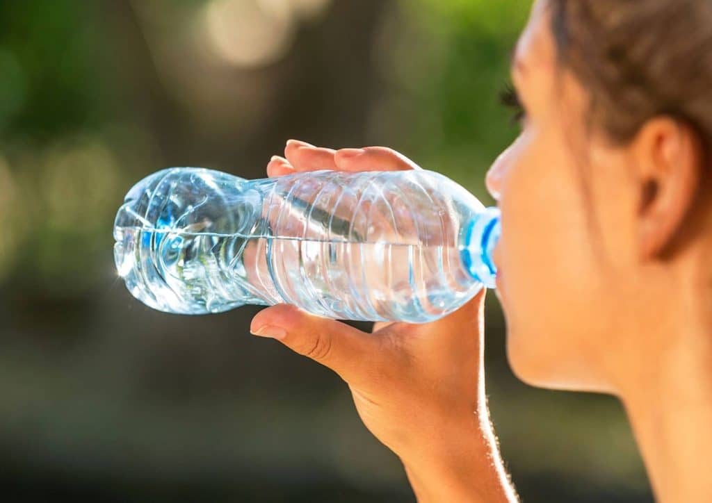 High Fibre Diet for Weight Loss: Why Fibre Keeps You Full 37 A woman takes a refreshing sip from a clear water bottle, enjoying hydration outdoors.