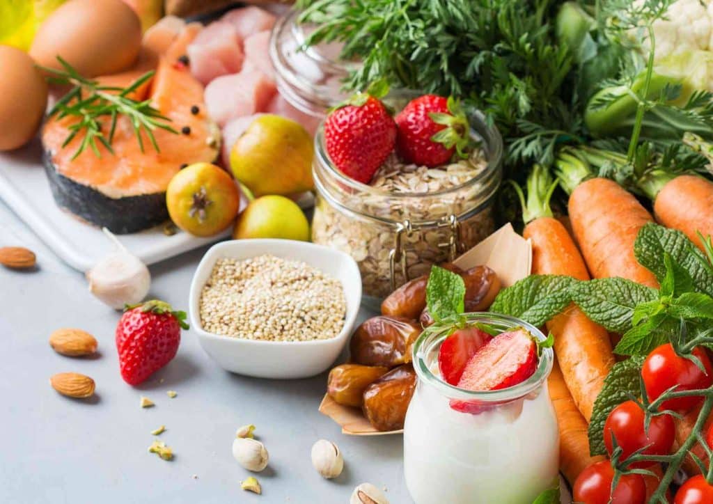 Is the Mediterranean Diet Good for Weight Loss? 13 An array of foods showcasing eggs, leafy vegetables, seasonal fruits, and different types of nuts on a wooden surface.