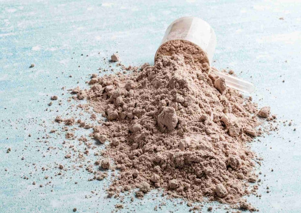 Is Whey Protein Good for Weight Loss? 38 A scoop of protein powder resting on a blue surface, showcasing its fine texture and light color.