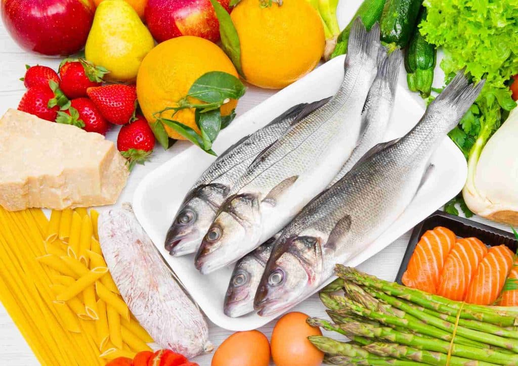 Is the Mediterranean Diet Good for Weight Loss? 26 A diverse selection of fresh fish alongside an array of vegetables and fruits, showcasing a healthy food market scene.
