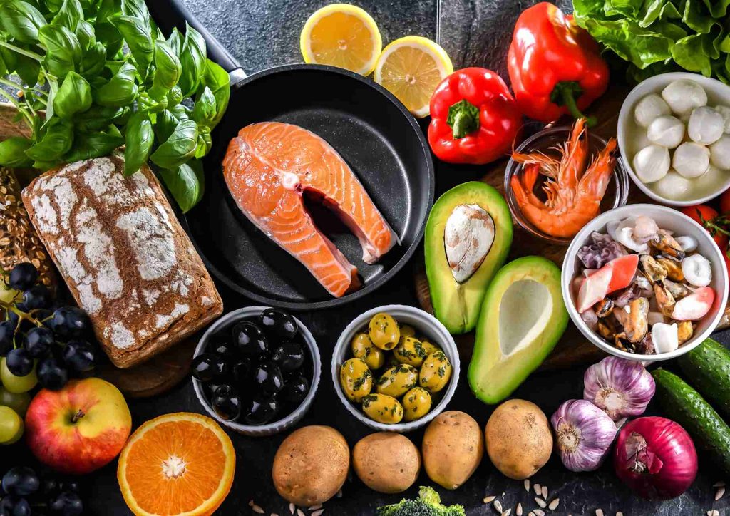 Is the Mediterranean Diet Good for Weight Loss? 28 A diverse spread of foods featuring fish, vibrant vegetables, ripe fruits, and mixed nuts displayed together.