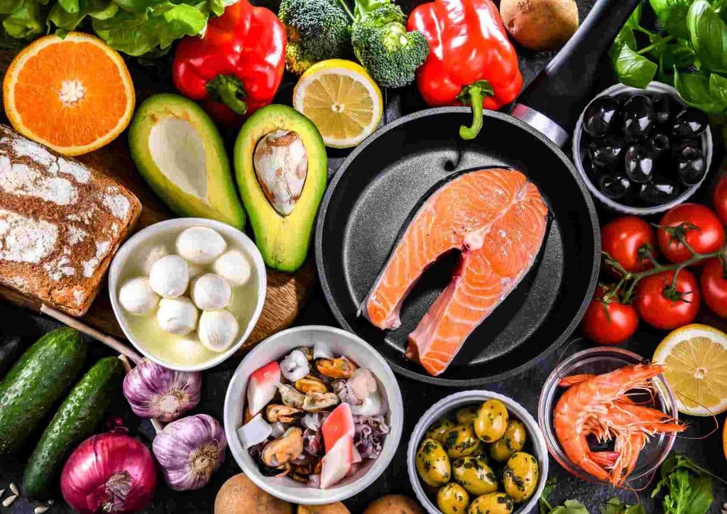 Is the Mediterranean Diet Good for Weight Loss? 30 A diverse spread of food items including fish, vibrant vegetables, and various fruits displayed together on a surface.