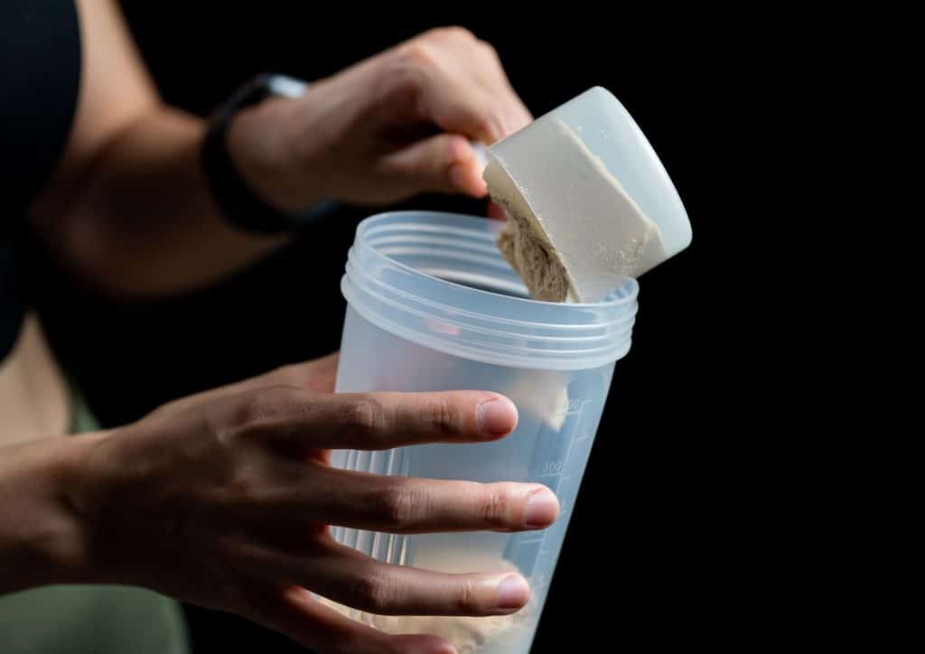 Is Whey Protein Good for Weight Loss? 30 A woman holds a container of protein powder, smiling and showcasing her fitness-focused lifestyle.
