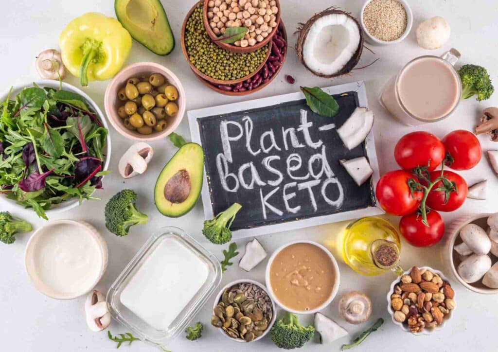 Keto vs Low Carb for Weight Loss: Which Is Better? 9 A vibrant display of keto-friendly plant foods, featuring avocados, seeds, and vegetables arranged on a wooden table.