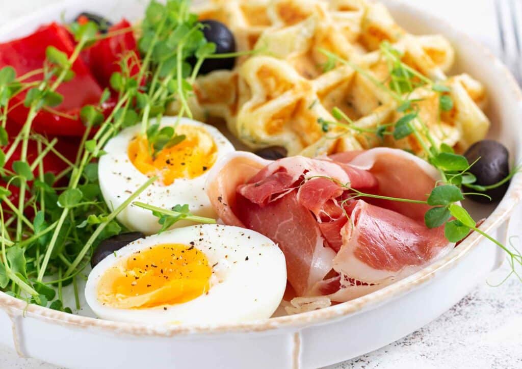 Keto vs Low Carb for Weight Loss: Which Is Better? 28 A plate featuring scrambled eggs, slices of ham, and a variety of colourful vegetables.