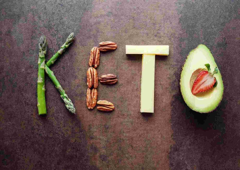 Keto vs Low Carb for Weight Loss: Which Is Better? 1 The word "keto" formed using avocado, asparagus, and various keto-friendly foods on a wooden surface.