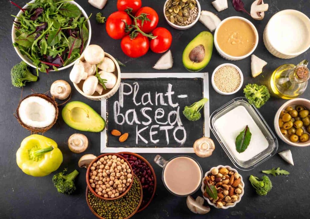 Keto vs Low Carb for Weight Loss: Which Is Better? 7 A vibrant display of keto-friendly plant foods, featuring avocados, seeds, and vegetables arranged on a wooden table.
