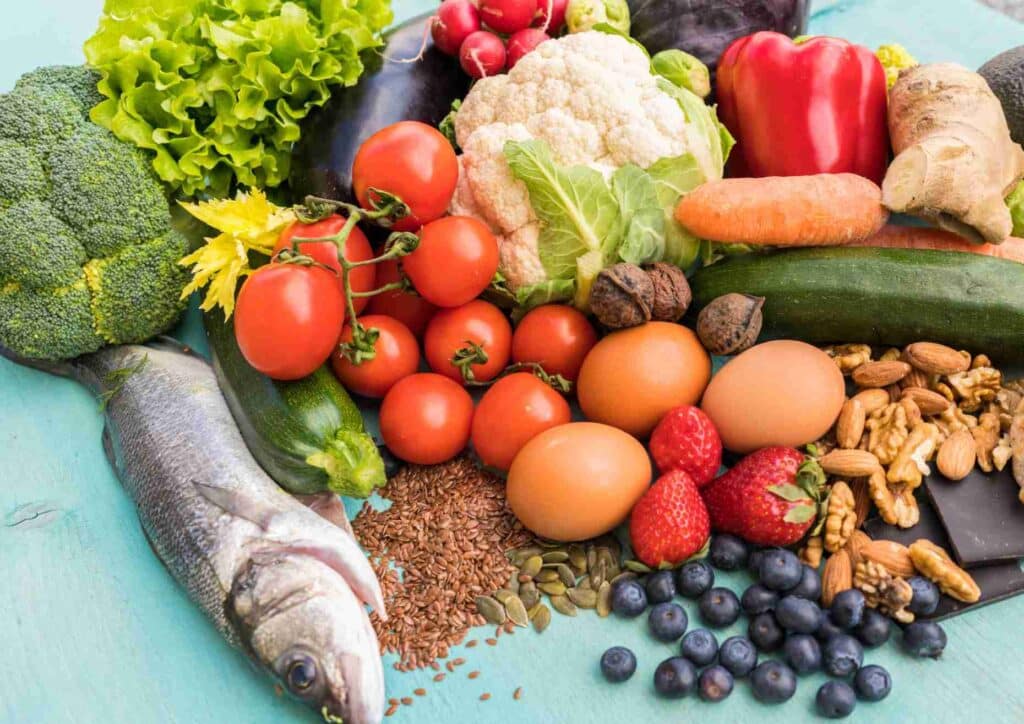 Keto vs Low Carb for Weight Loss: Which Is Better? 18 An array of fresh fruits and vegetables neatly arranged on a blue table, highlighting their diverse shapes and colours.