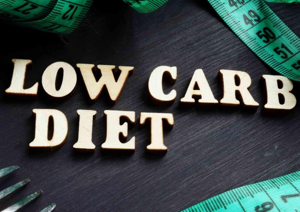 Keto vs Low Carb for Weight Loss: Which Is Better? 15 A variety of low-carb foods including leafy greens, nuts, and lean proteins arranged on a wooden table for a nutritious diet.