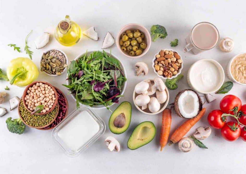 Keto vs Low Carb for Weight Loss: Which Is Better? 24 A variety of foods including colourful vegetables, nuts, and other ingredients arranged on a wooden surface.