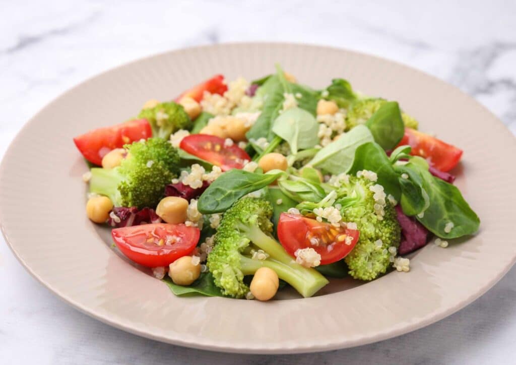 Keto vs Low Carb for Weight Loss: Which Is Better? 25 A plate featuring a colourful salad with broccoli, tomatoes, chickpeas, and fresh spinach leaves.