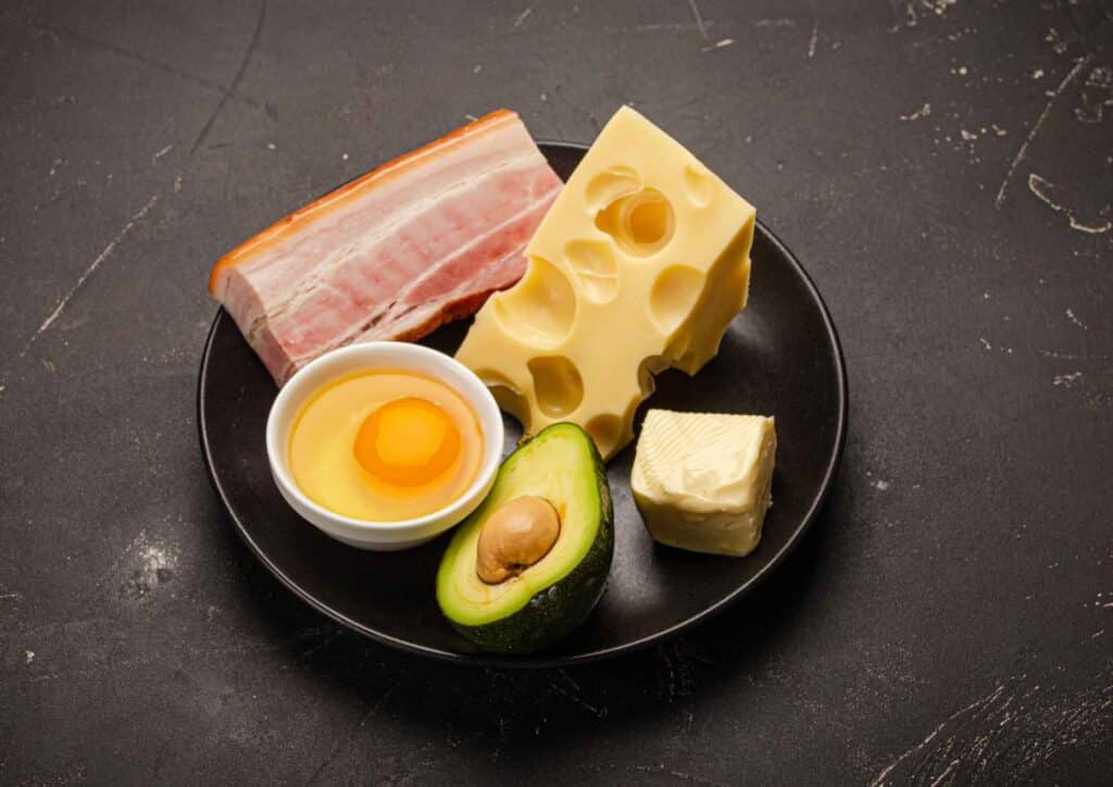 Keto vs Low Carb for Weight Loss: Which Is Better? 35 A plate featuring slices of cheese, cooked eggs, and crispy bacon arranged appetizingly.