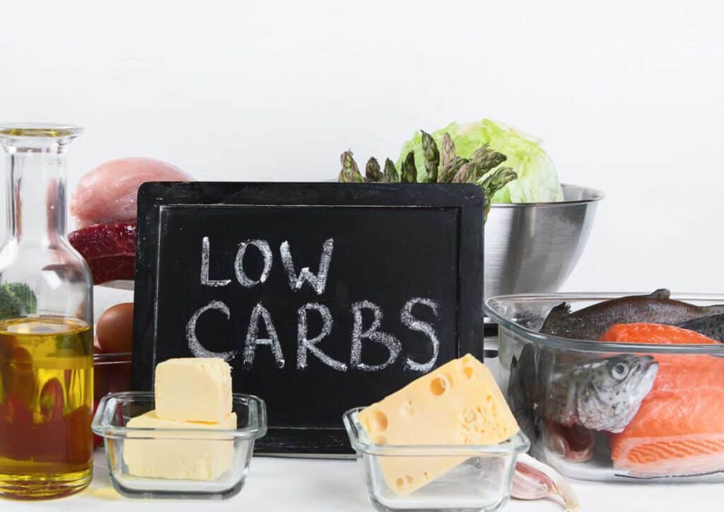 Keto vs Low Carb for Weight Loss: Which Is Better? 40 A variety of low carb foods including vegetables, meats, and nuts arranged on a wooden table.