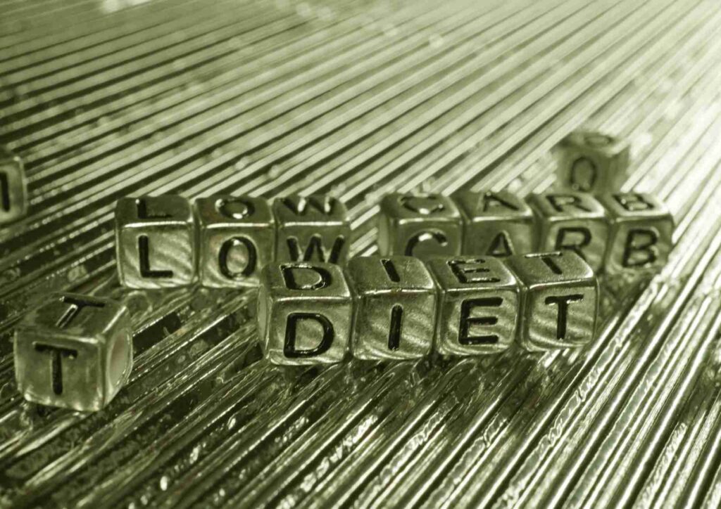 Keto vs Low Carb for Weight Loss: Which Is Better? 42 A variety of low-carb meal options displayed, featuring leafy greens, grilled chicken, and avocados on a white plate.