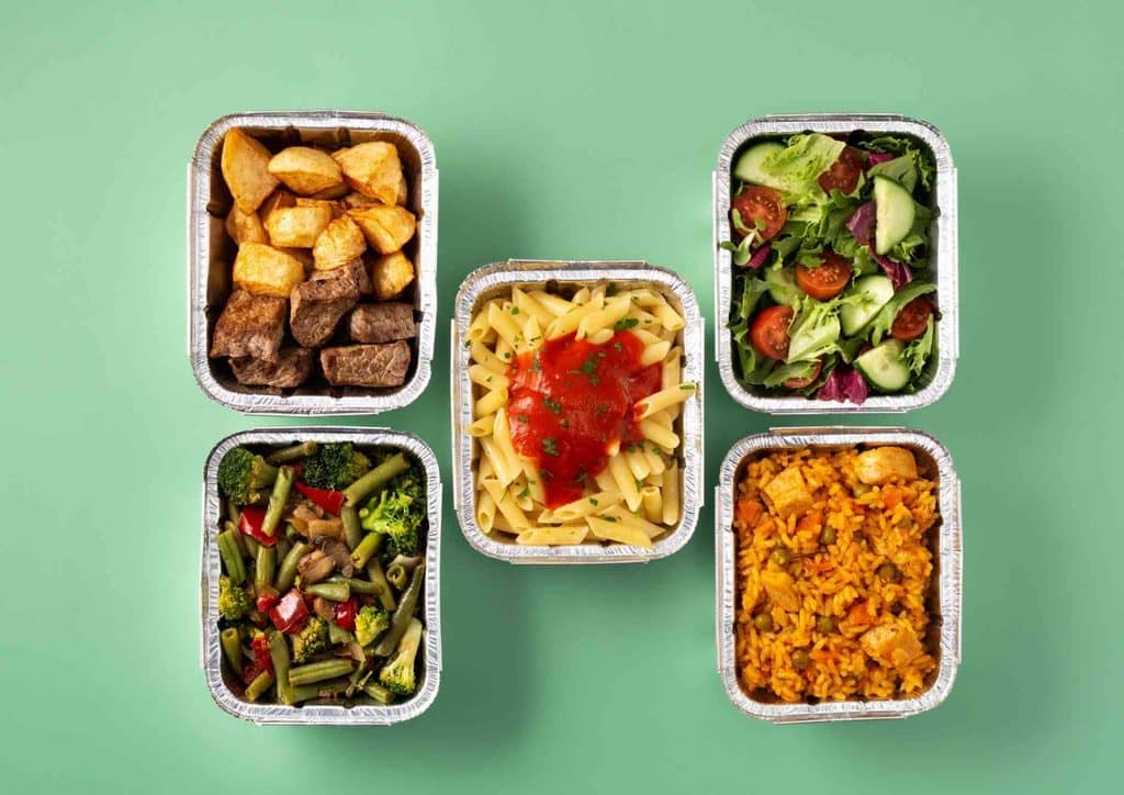 Healthy Lunches for Weight Loss: Work and Home Ideas 21 Four food containers arranged in a row, set against a vibrant green background.