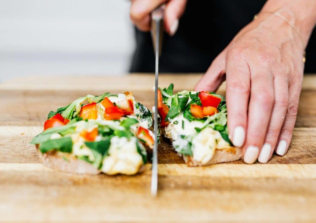 Healthy Lunches for Weight Loss: Work and Home Ideas 18 A person using a knife to slice open a loaf of bread on a wooden cutting board.