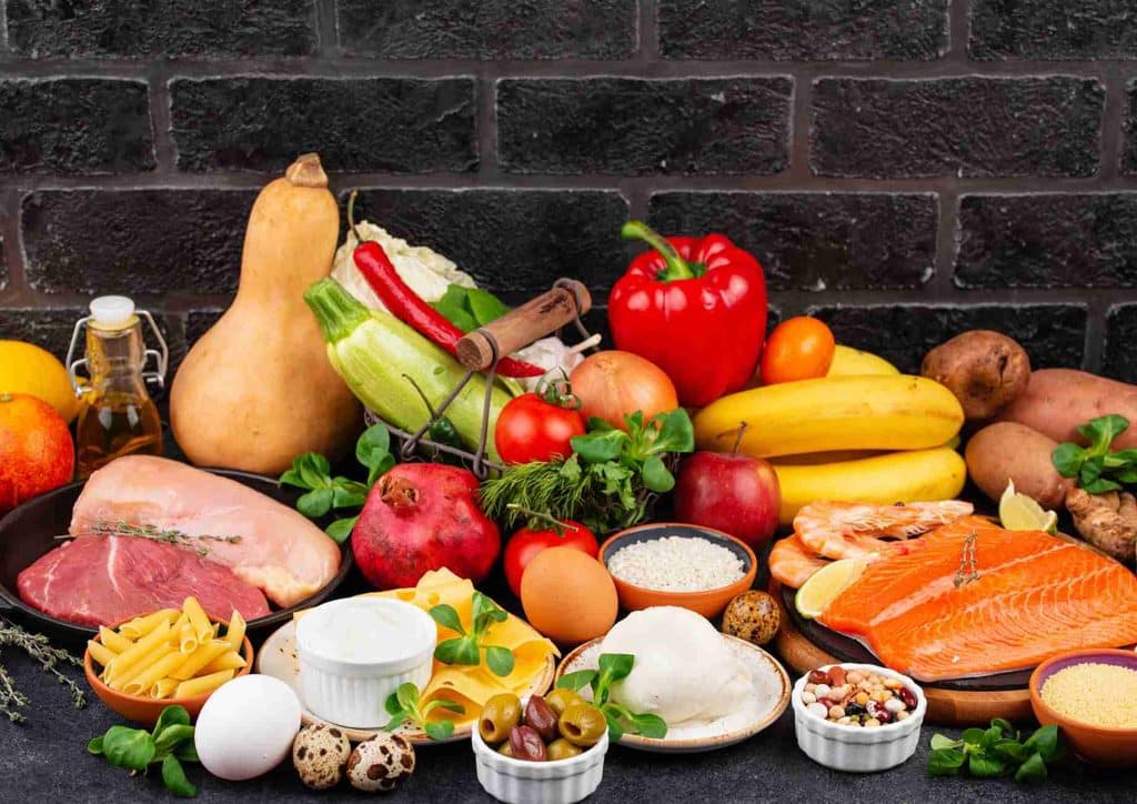 Is the Mediterranean Diet Good for Weight Loss? 34 A variety of foods including fish, corn, and oranges arranged on a wooden table.