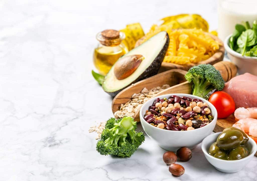 Is the Mediterranean Diet Good for Weight Loss? 36 A diverse assortment of foods including meat, fresh vegetables, nuts, and a glass of milk arranged on a wooden table.