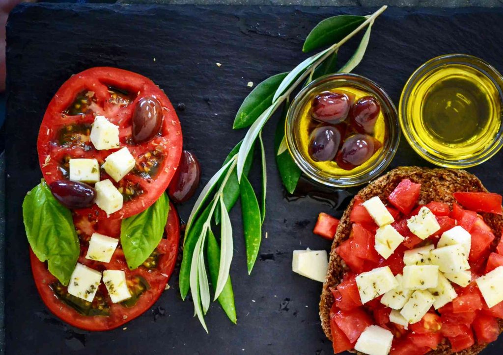 Is the Mediterranean Diet Good for Weight Loss? 38 A plate featuring fresh tomatoes, slices of cheese, and black olives arranged artfully.