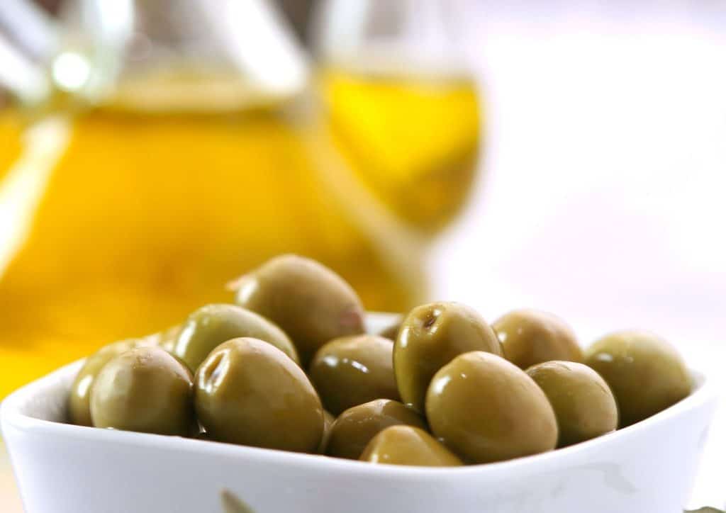 Is the Mediterranean Diet Good for Weight Loss? 27 A bowl of olives surrounded by a bottle of olive oil and a small dish of olive oil.