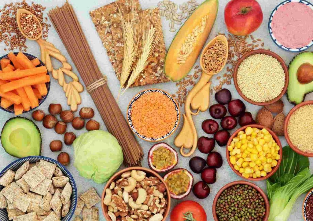 High Fibre Diet for Weight Loss: Why Fibre Keeps You Full 25 An assortment of nuts, seeds, fruits, vegetables, and grains displayed together on a wooden surface.