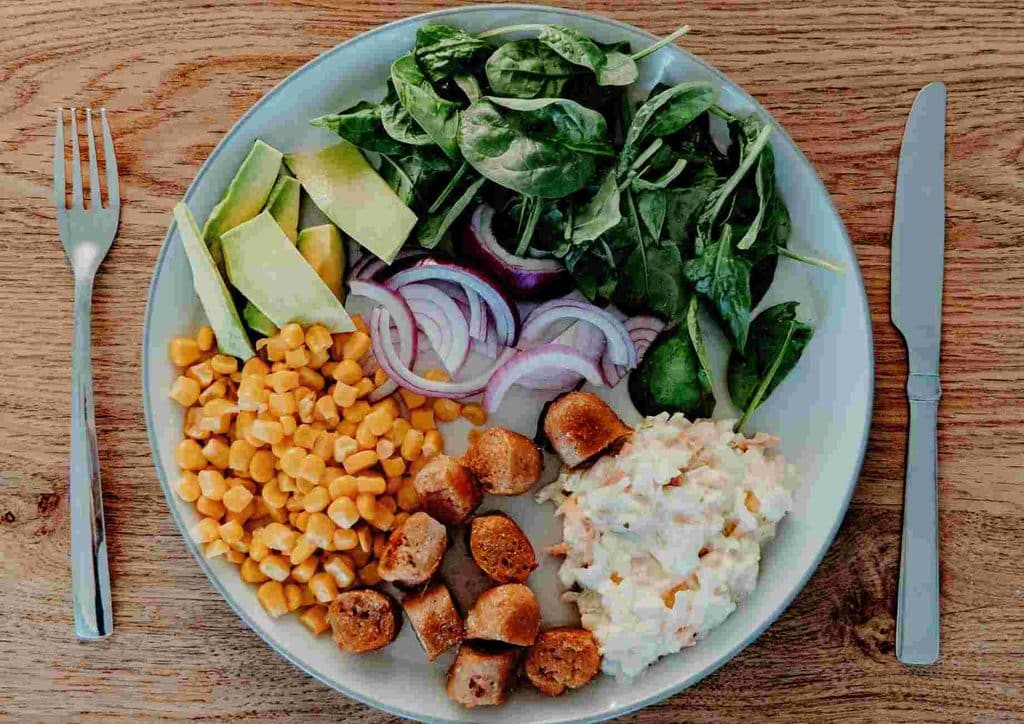 Postpartum Weight Loss: A Gentle, Realistic Guide 14 A well-presented plate of assorted dishes featuring vibrant vegetables and grains, set on a rustic wooden table.