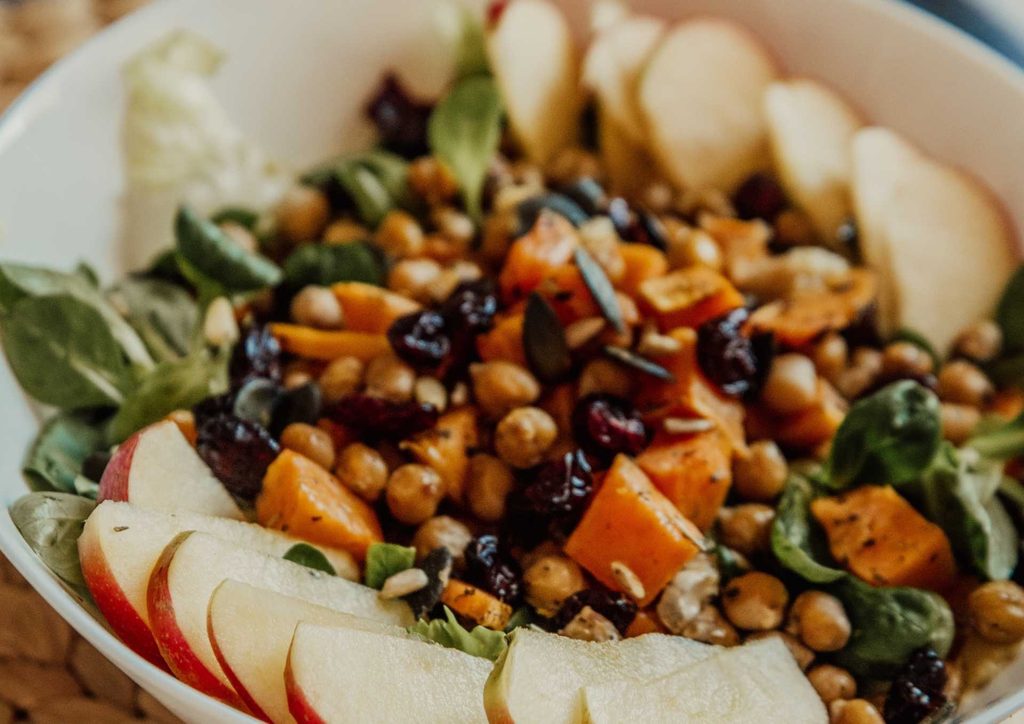 Vegetarian Diet for Weight Loss: How to Get It Right 29 A bowl of salad featuring fresh greens, sliced apples, nuts, and chickpeas, arranged attractively.