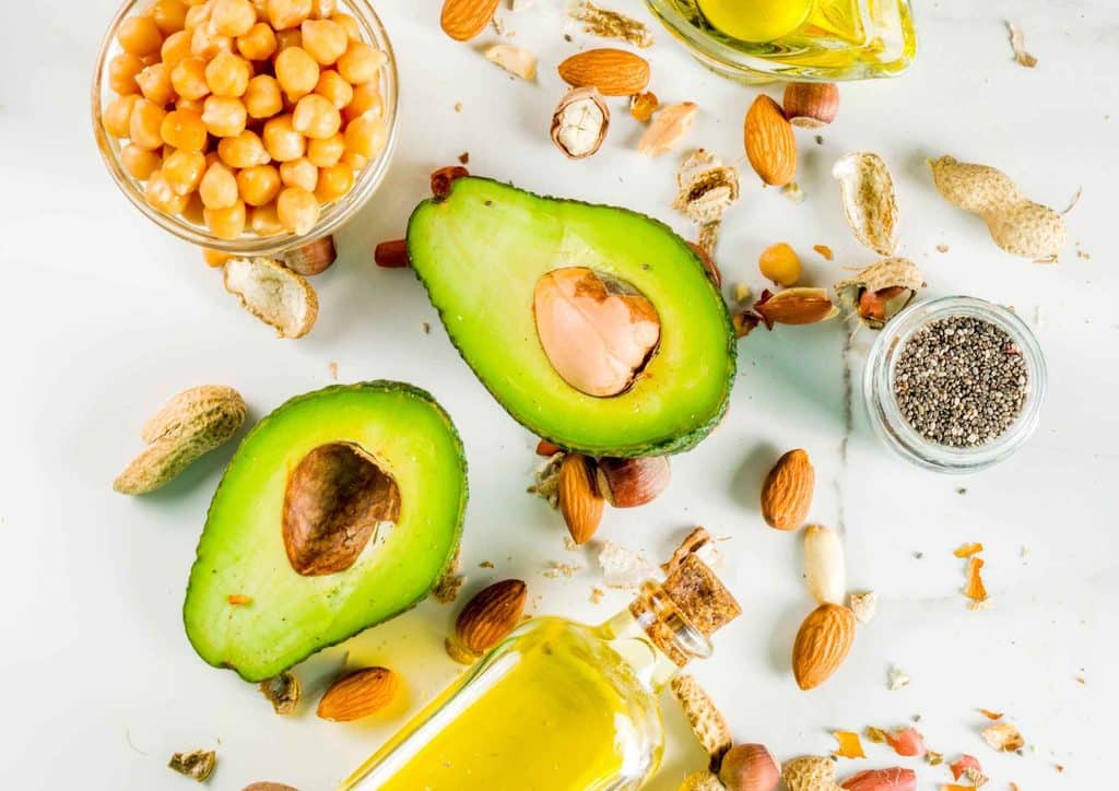 Postpartum Weight Loss: A Gentle, Realistic Guide 22 A variety of healthy foods including avocado, nuts, beans, and seeds arranged on a white surface
