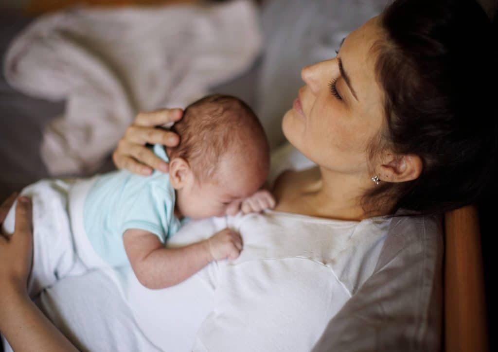 Postpartum Weight Loss: A Gentle, Realistic Guide 29 A woman gently cradles her newborn baby in her arms, showcasing a tender moment of maternal affection.