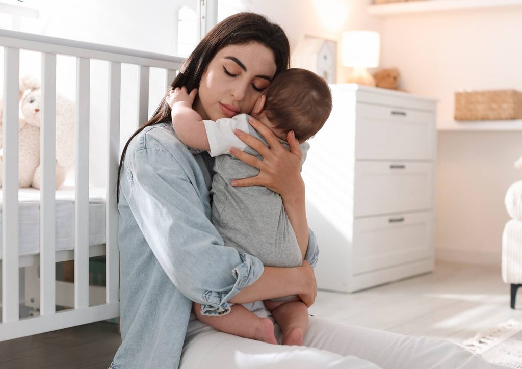 Postpartum Weight Loss: A Gentle, Realistic Guide 34 A woman gently cradles a baby in her arms, showcasing a tender moment of care and affection.