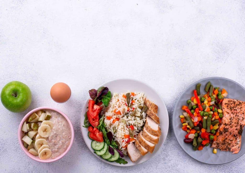Healthy Dinners for Weight Loss: Easy Weeknight Ideas 10 An assortment of three plates displaying a salad, roasted chicken, and a variety of vegetables, showcasing a nutritious spread.