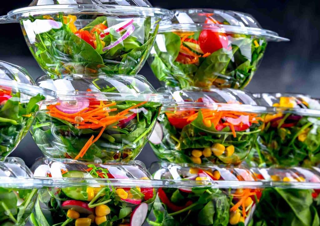 Easy Meals for Weight Loss When You're Short on Time 27 A stack of clear plastic containers filled with colourful salads, showcasing various vegetables and toppings.