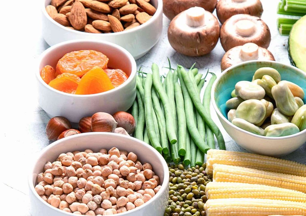 High Fibre Diet for Weight Loss: Why Fibre Keeps You Full 23 An array of diverse foods featuring nuts, beans, corn, and assorted vegetables displayed together on a table.