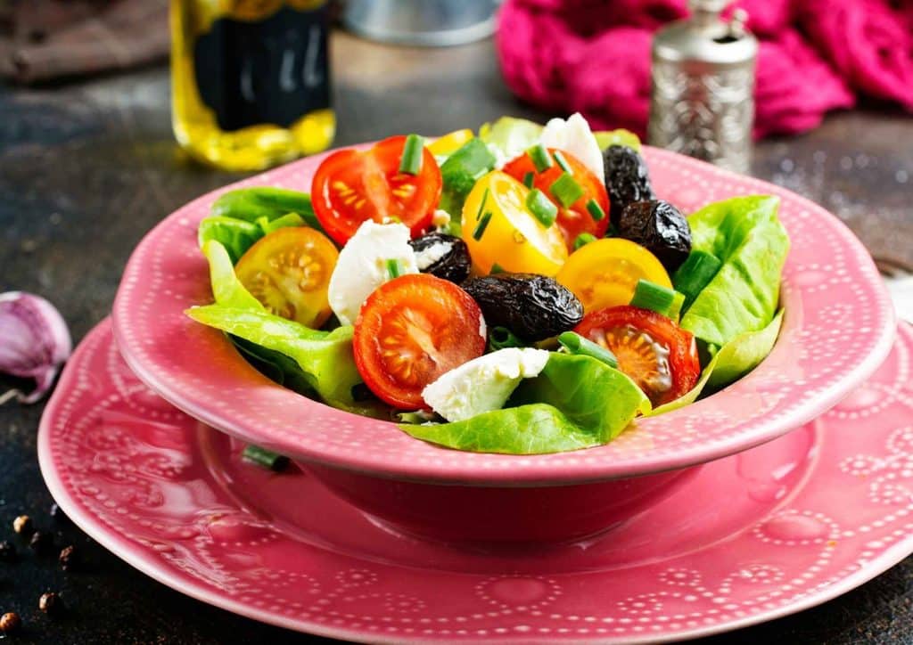 High Fibre Diet for Weight Loss: Why Fibre Keeps You Full 22 A vibrant salad composed of ripe tomatoes, green olives, and feta cheese, arranged attractively in a bowl.