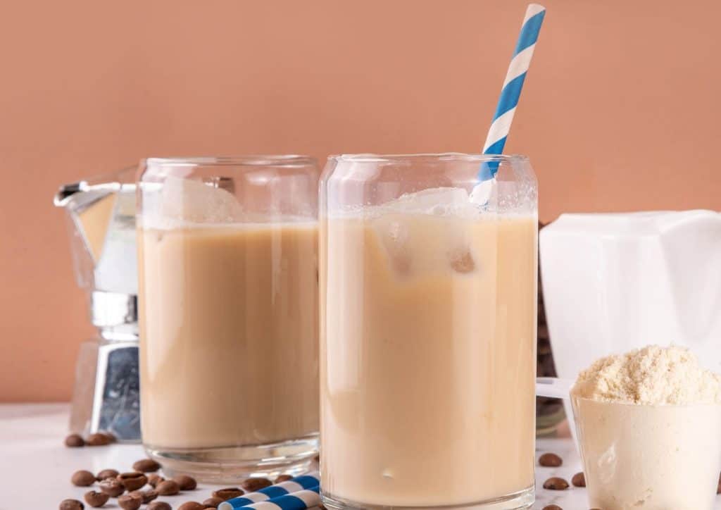 Is Whey Protein Good for Weight Loss? 26 Two glasses of iced coffee topped with ice cream, accompanied by scattered coffee beans on a wooden surface.