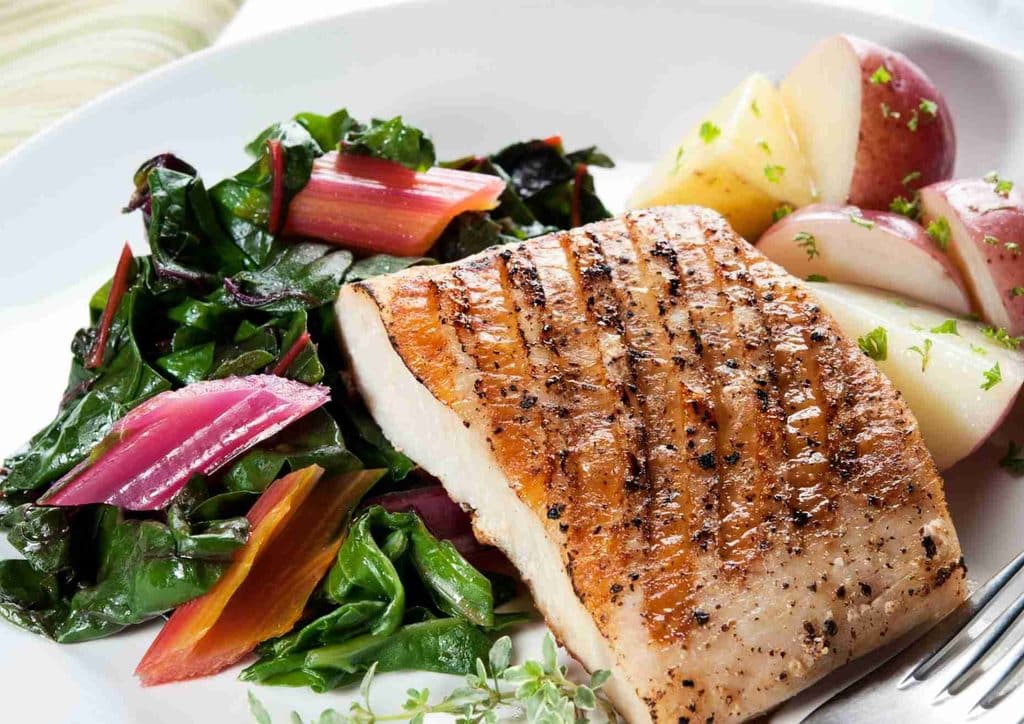 Healthy Dinners for Weight Loss: Easy Weeknight Ideas 25 Grilled salmon fillet served with roasted potatoes and a side of sautéed greens on a white plate.