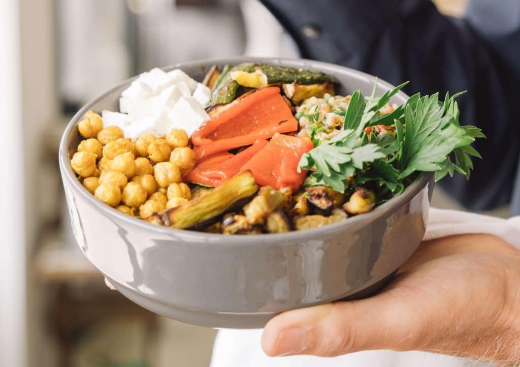 Healthy Lunches for Weight Loss: Work and Home Ideas 15 A person holds a bowl filled with colourful vegetables and various ingredients, ready for a meal preparation.